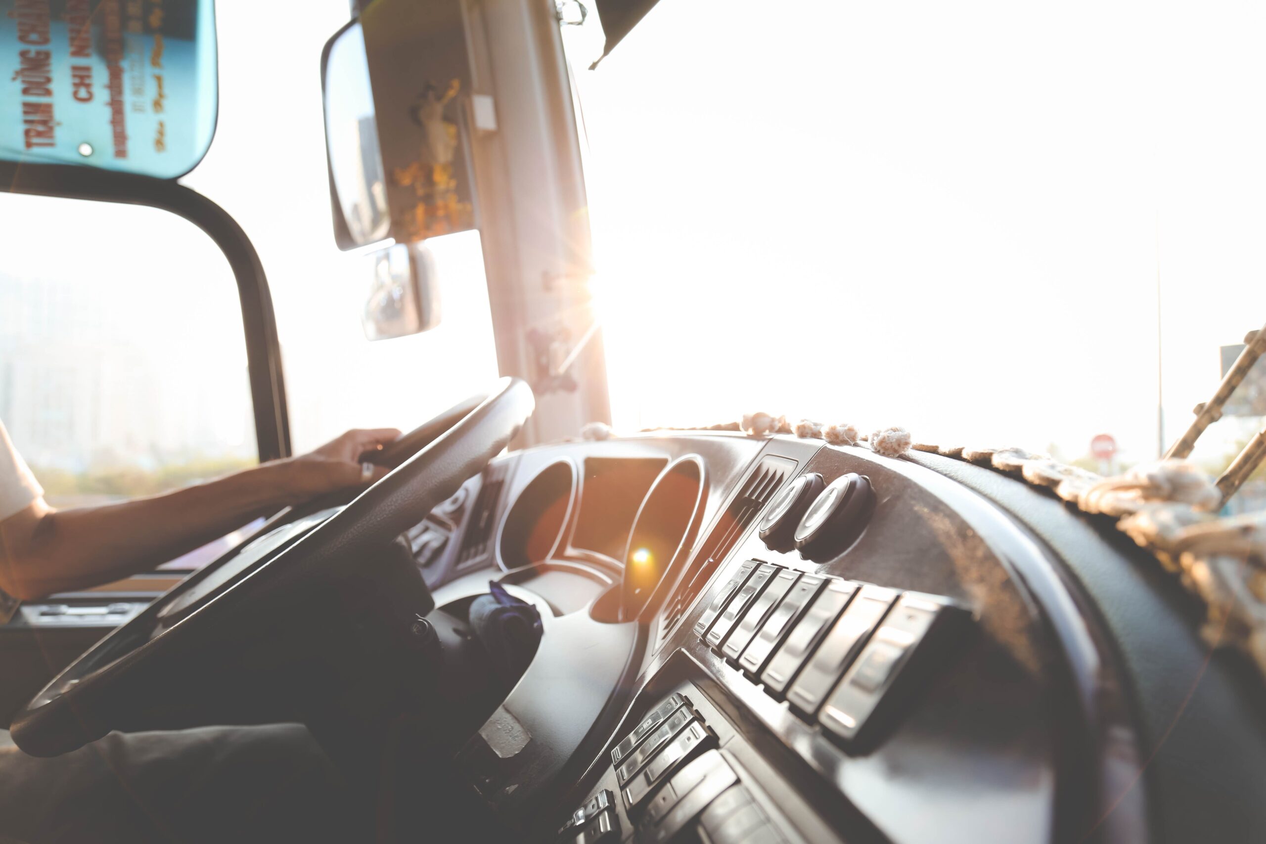 A man driving a truck, sunlight streaming through the windshield, highlighting the interior and his focused expression.