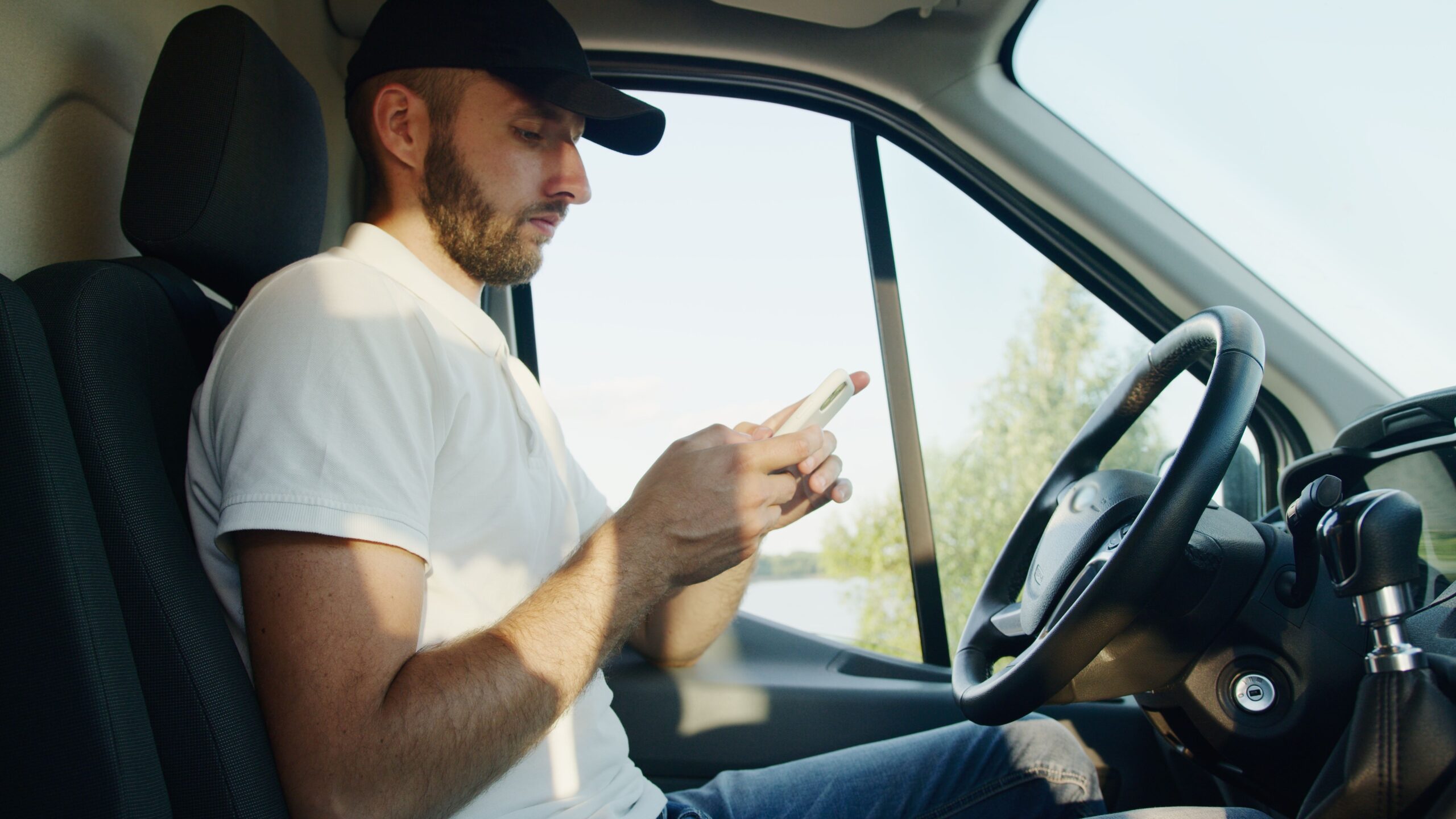 A man in a truck is using his cell phone while seated in the driver's seat.