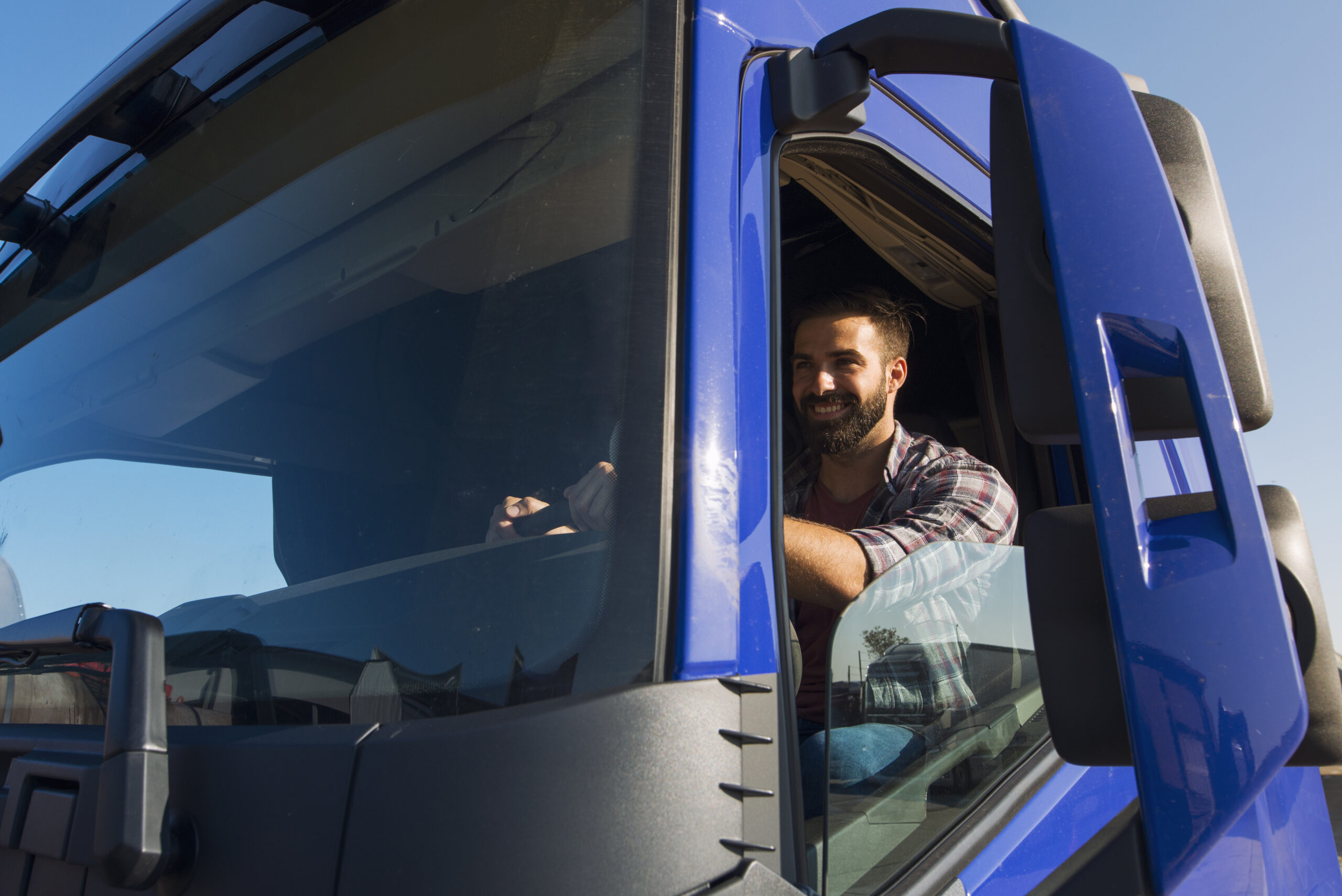 A man seated in the driver's seat of a truck, representing the profession of truck driving and its associated salary.